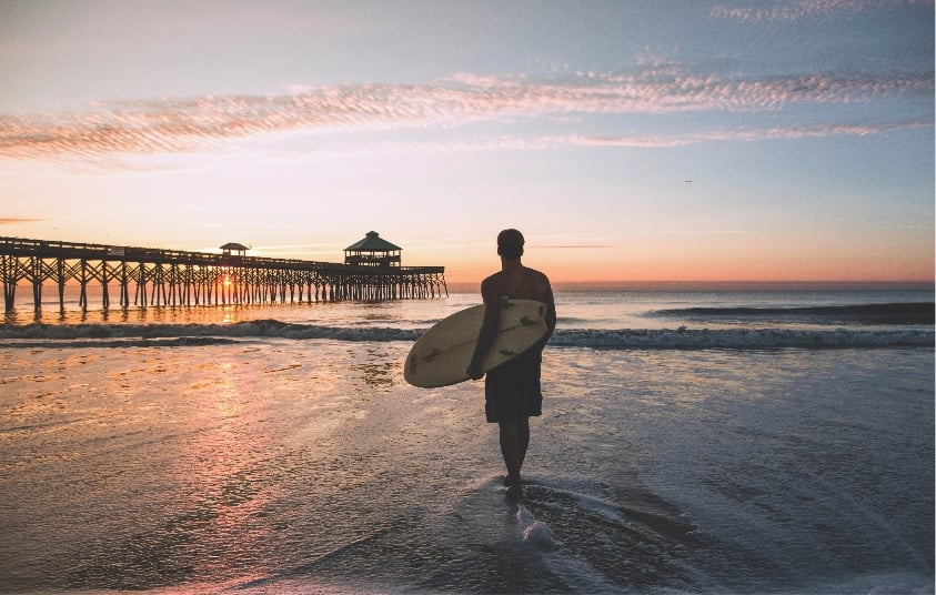 a surfer looks at a sunset
